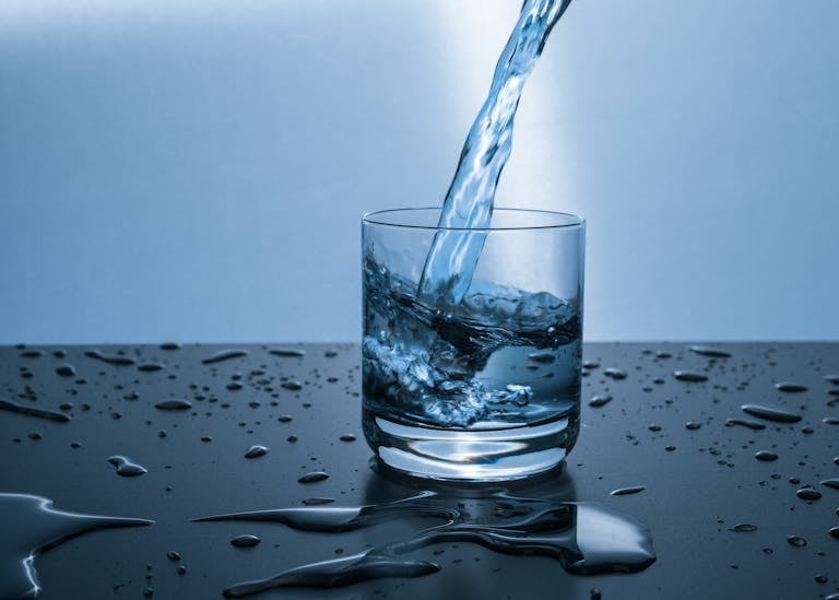 High-quality image of water being poured into a glass, illustrating hydration and purity.